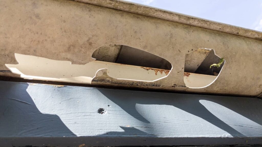 Gutter on a roof with a hole from hail storm damage.