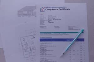 REScheck compliance certificate showing project details and envelope assemblies with R-values and U-factors, on top of house plans