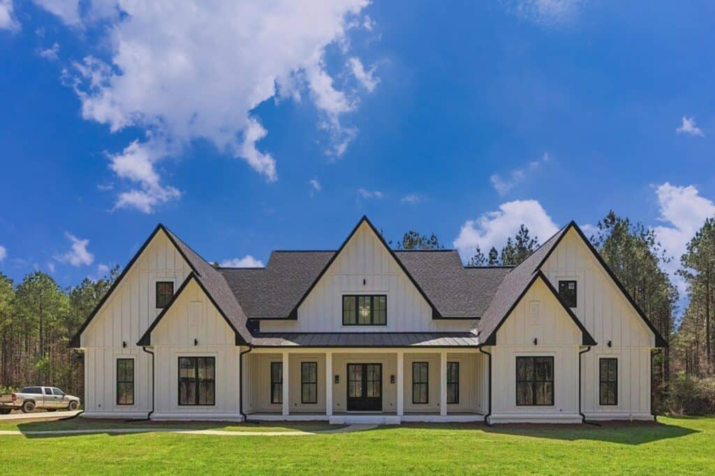 White modern farmhouse with a dark shingle roof and metal porch roof in rural Mississippi