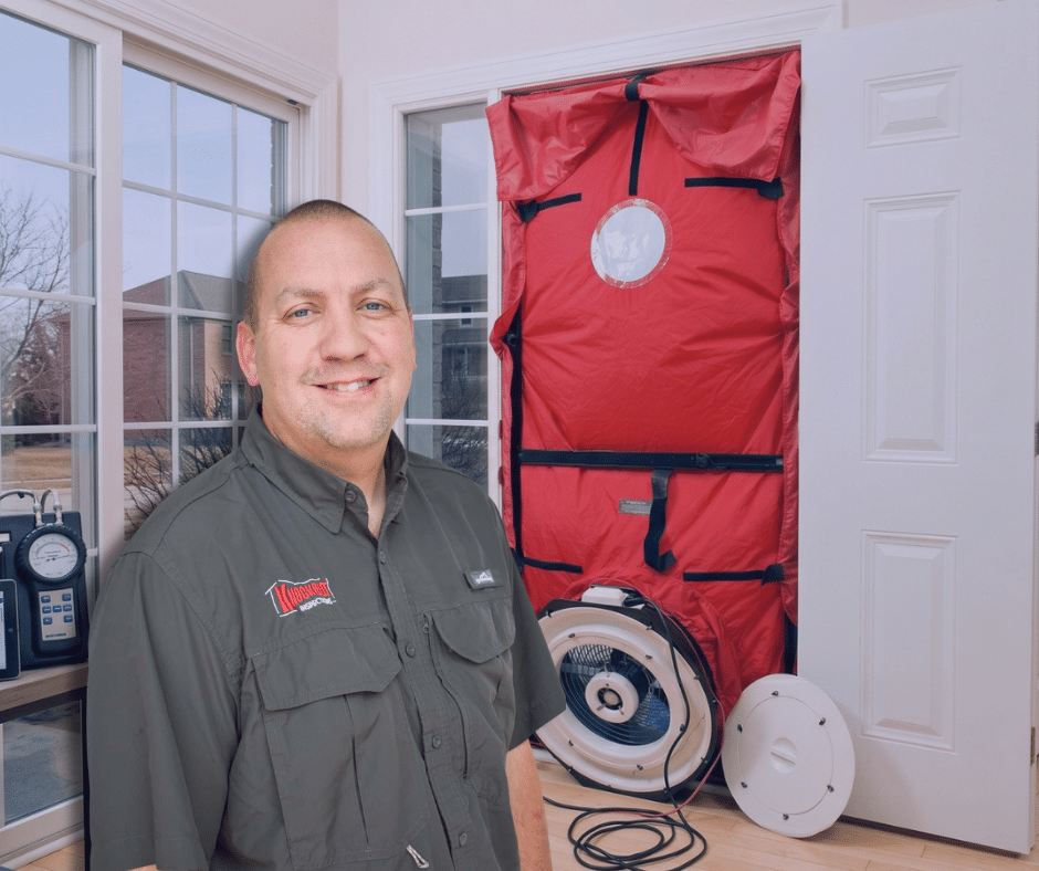 Knockout inspector beside a blower door fan set up for a home energy assessment