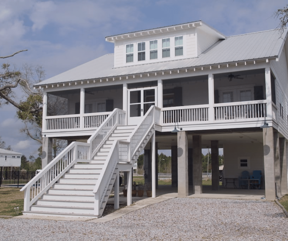 Elevated coastal Mississippi home on concrete piers with a white metal roof and screened porches